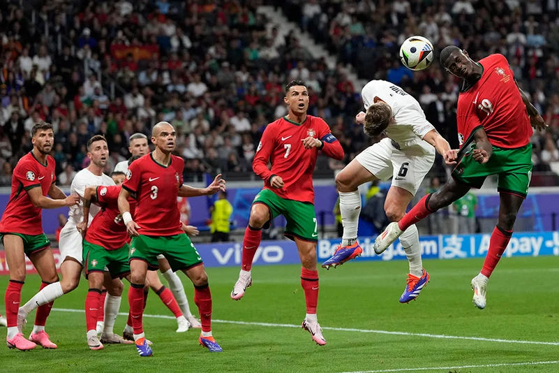 Nuno Mendes heads the ball next to Jaka Bijol 